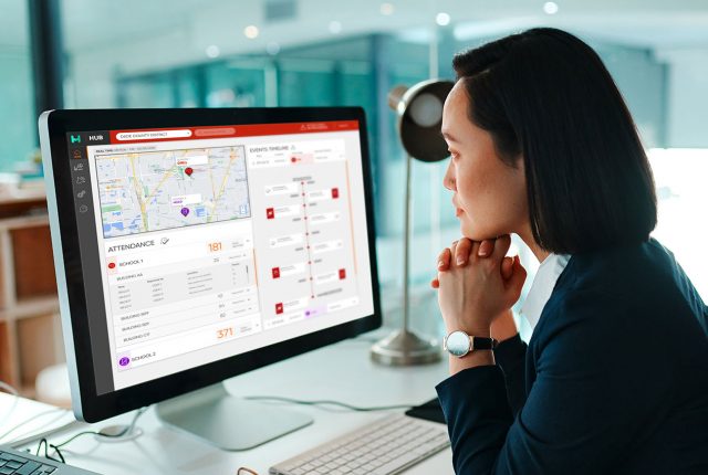 Woman in an office closely monitoring an event map and details through the Protect Detect dashboard on a large desktop screen.